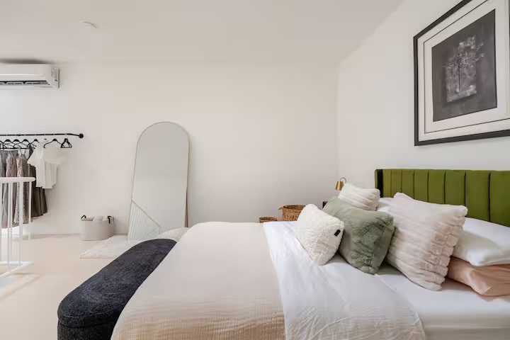Bedroom with green velvet headboard and clothing rail